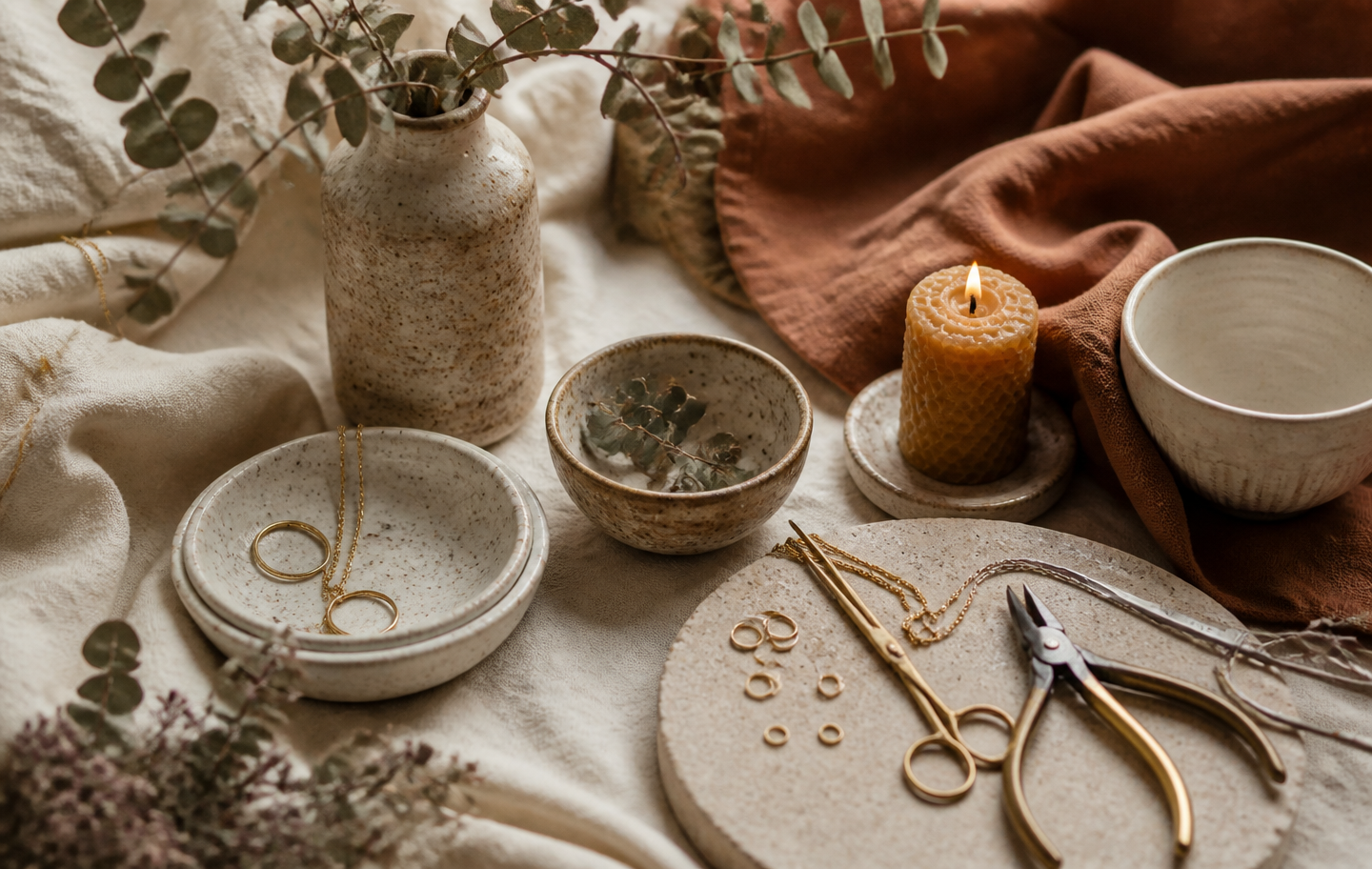 Handmade ceramics and jewelry arranged on linen